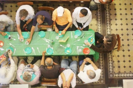 Families sharing a meal together around a long communal table.